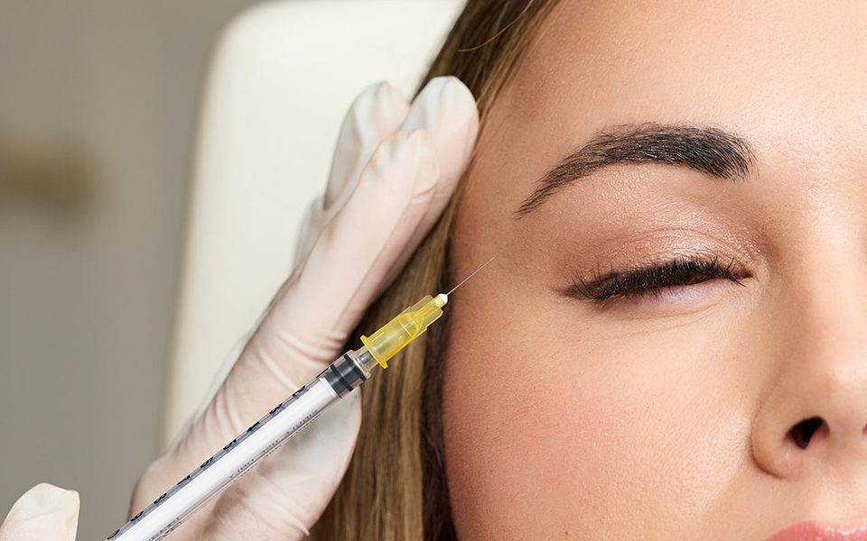 Injector placing Botox near a woman's outer brow